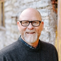 Smiling professional with glasses, circular portrait